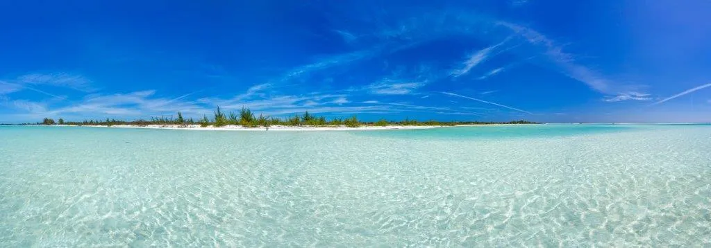 Klares Wasser und blauer Himmel an einem tropischen Strand.