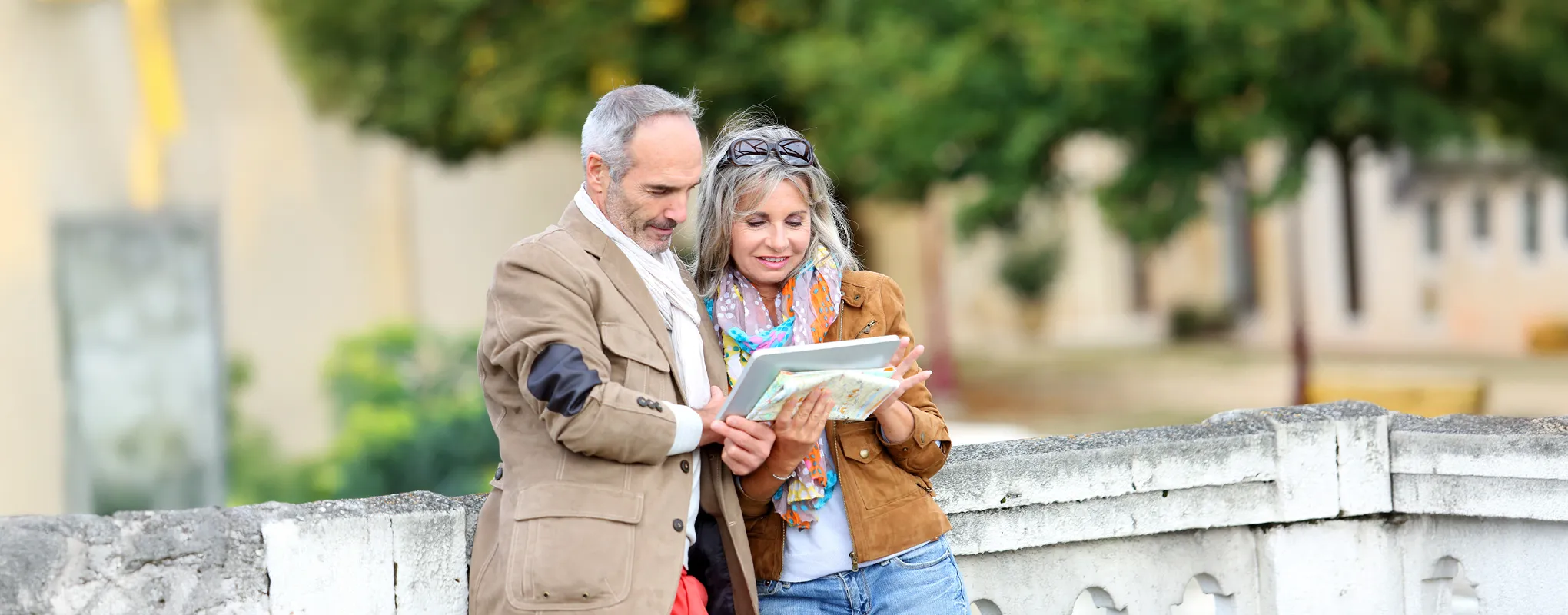 Paar liest Karte auf Brücke, entspannte Stimmung, grüne Umgebung.