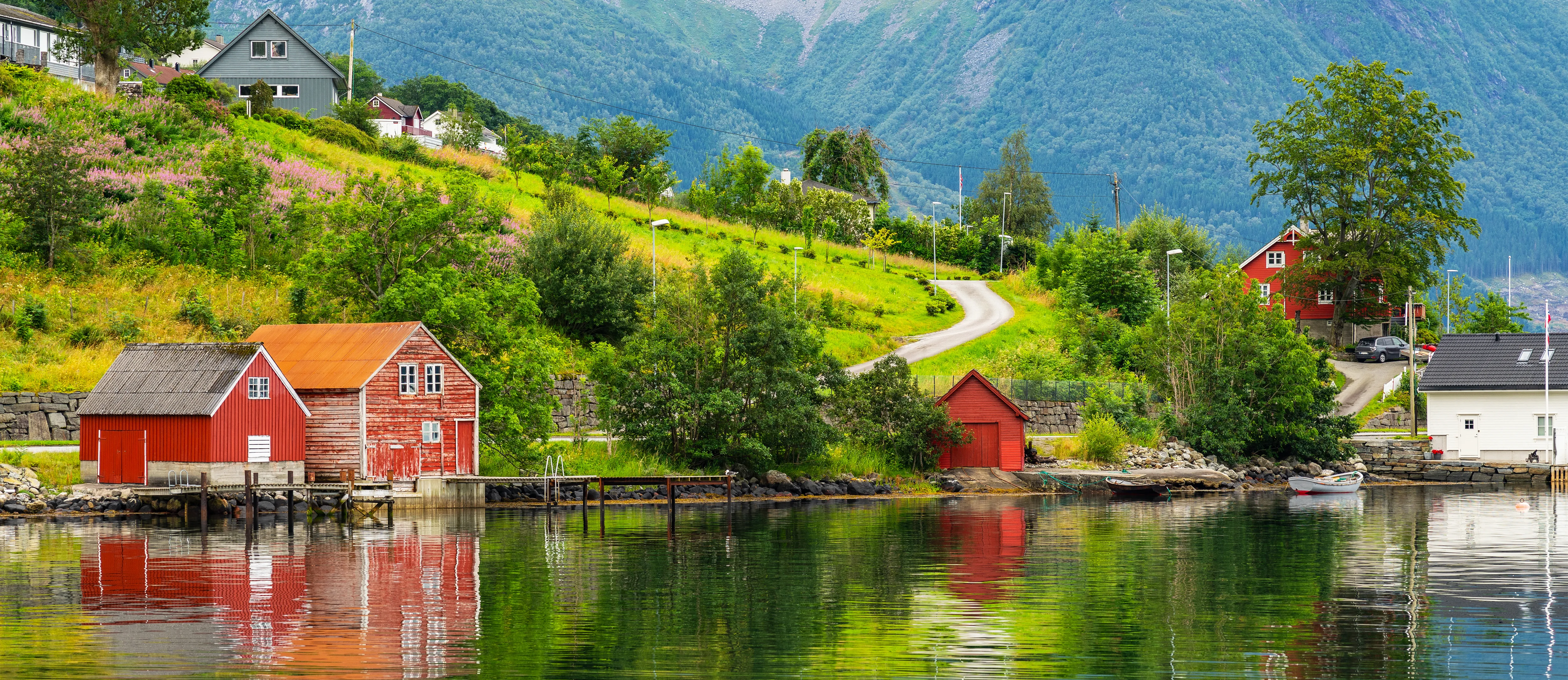 Rote Holzhäuser am Fjord in skandinavischer Landschaft.