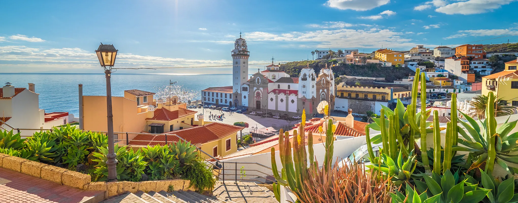 Bunte Küstenstadt mit Kirche und Meerblick unter blauem Himmel.