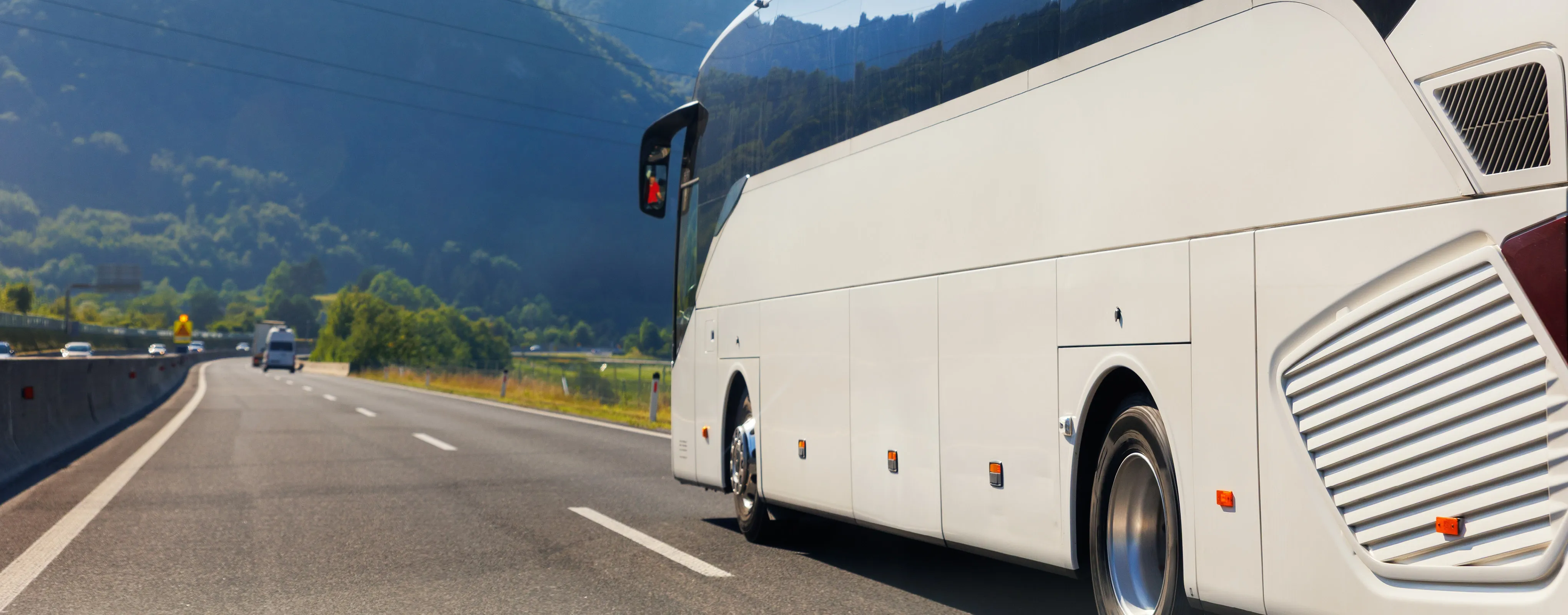 Sonnenbeschienene Küstenstraße mit Auto und Meerblick.