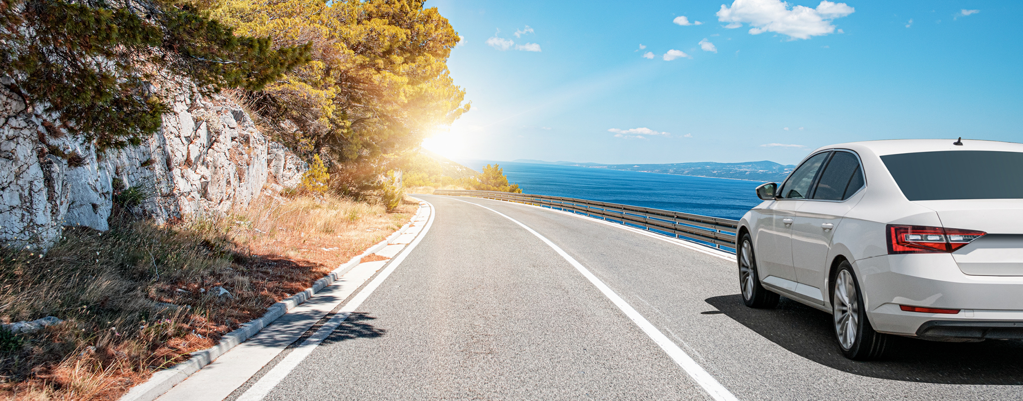 Auto auf sonniger Küstenstraße mit Meerblick.