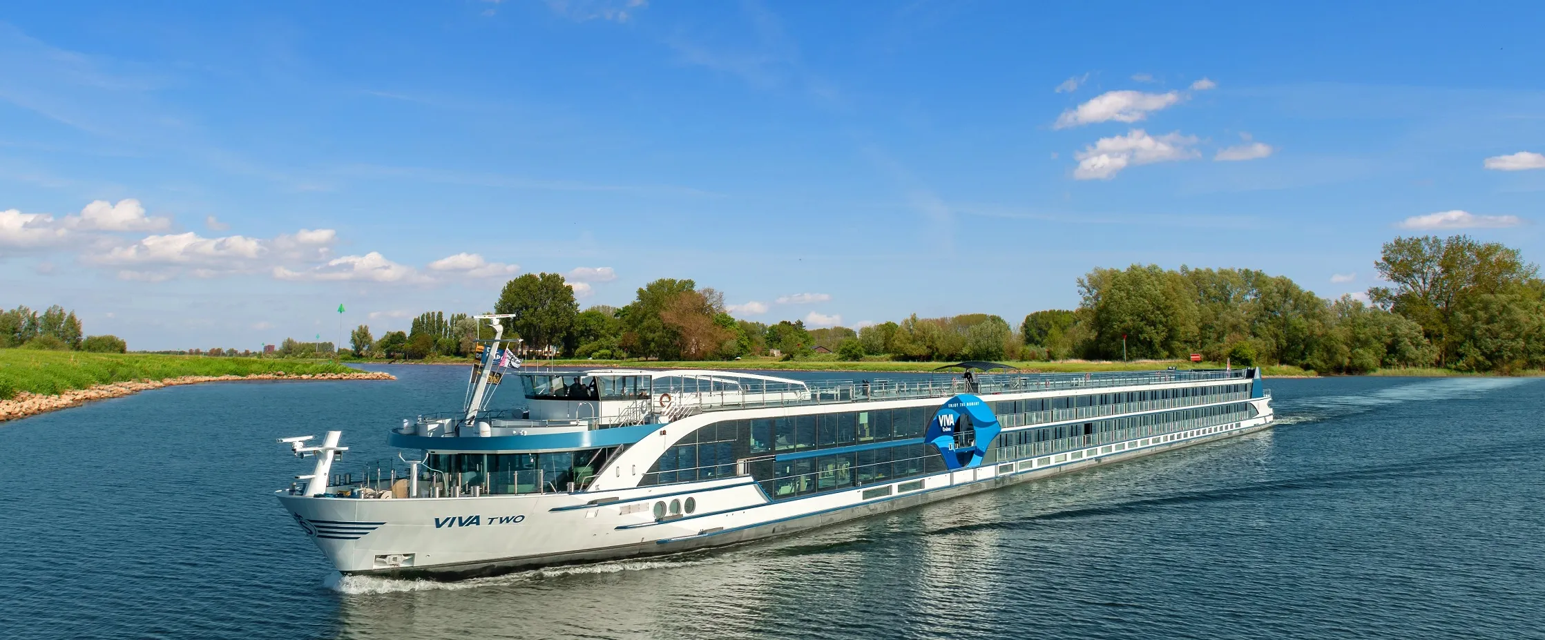Modernes Flusskreuzfahrtschiff auf ruhigem Fluss bei Sonnenschein
