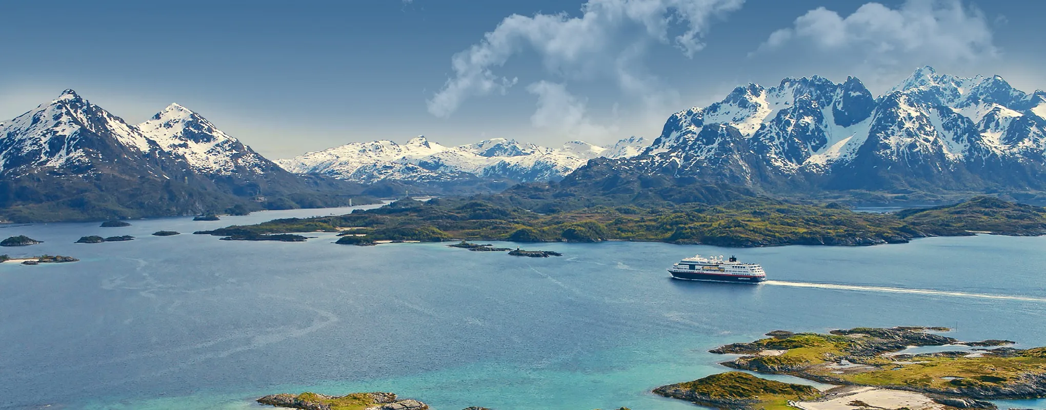 Schiff vor schneebedeckten Bergen in Norwegen, ruhige See, klare Luft.