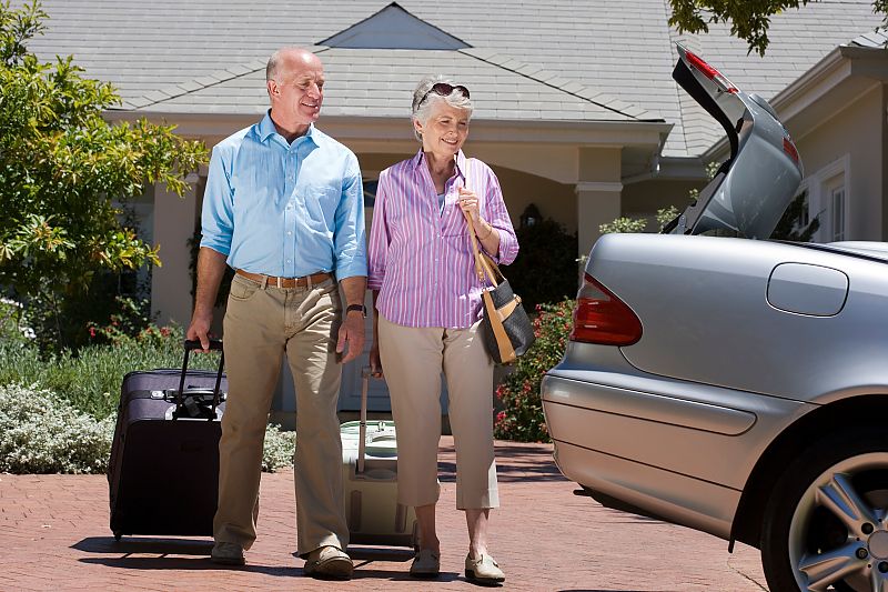 Älteres Paar mit Koffern, bereit für eine entspannte Reise.