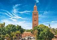 Koutoubia-Moschee in Marrakesch vor blauem Himmel und Palmen.