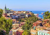 Bunte Häuser in Valparaíso mit Blick auf das Meer bei klarem Himmel.