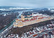 Luftaufnahme von Stift Melk im Winter, umgeben von Schnee und Fluss.