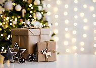 Geschenke vor Weihnachtsbaum, festliche Stimmung mit Lichtern.