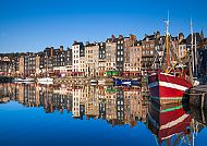 Bunte Boote und Häuser spiegeln sich im Hafen von Honfleur.