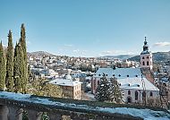 Winterliche Stadtansicht mit Kirche und verschneiten Dächern.
