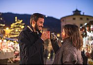 Paar genießt heißen Glühwein auf einem festlichen Weihnachtsmarkt.