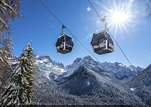 Seilbahn über verschneiten Bergen bei Sonnenschein.