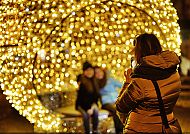 Person fotografiert leuchtende Weihnachtsdekoration bei Nacht.
