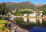 Idyllische Landschaft mit Bergen, Fluss und weißen Häusern.