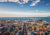 Blick über Reykjavik mit bunten Häusern und blauem Himmel.