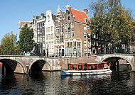 Grachtentour Amsterdam, Grachtentour in Amsterdam mit historischen Gebäuden und Brücke.