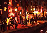 Amsterdam Nightlifetour, Belebte Straßenszene im Rotlichtviertel von Amsterdam bei Nacht., Belebtes Nachtleben in Amsterdam entlang eines beleuchteten Kanals.