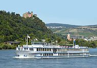 MPS REMBRANDT VAN RIJN, MPS REMBRANDT VAN RIJN auf malerischer Flusskreuzfahrt., Flusskreuzfahrtschiff vor malerischer Landschaft mit Burg und Kirche.