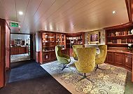 Bibliothek an Bord, Gemütliche Schiffsbibliothek mit eleganten Sesseln und Regalen., Gemütliche Bibliothek an Bord mit eleganten Sesseln und Regalen.