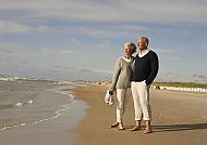 Jütland, Paar spaziert am Strand von Jütland, Dänemark, unter blauem Himmel.