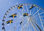 wheel_of_gothenburg, Riesenrad in Göteborg mit schwedischen Flaggen vor blauem Himmel., Riesenrad in Göteborg mit schwedischen Flaggen vor blauem Himmel.