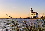 Ijsselmeer, Leuchtturm am Ijsselmeer bei Sonnenuntergang, Holland., Leuchtturm am Ijsselmeer bei Sonnenuntergang, umgeben von Schilf.