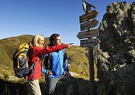 Salzburger-Land_Saalbach_Wandern, Wanderer in Saalbach genießen die Alpenlandschaft., Wanderer in Saalbach vor Wegweiser, sonnige Berglandschaft.