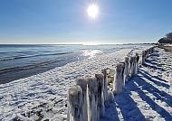 Ostsee im Winter, Verschneiter Ostseestrand unter strahlender Wintersonne., Winterliche Ostseeküste mit vereisten Holzpfählen im Sonnenschein.
