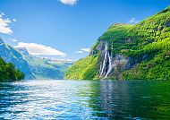 Geiranger, Majestätischer Geirangerfjord mit Wasserfall und grünen Bergen.