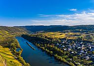 Malerische Flusslandschaft mit Dorf und grünen Hügeln., Idyllische Flusslandschaft mit Weinbergen und Dorf im Sonnenschein.