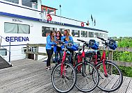 Radfahrergruppe vor dem Schiff Serena, bereit für die Tour., Radfahrer vor dem Schiff Serena bei einer Routenbesprechung.