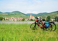 Fahrräder vor malerischer Donau-Landschaft mit Dorf im Hintergrund.