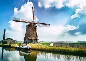 Windmühle am Kanal bei sonnigem Himmel und Wolken.