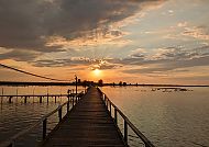 Sonnenuntergang über einem Steg am ruhigen See