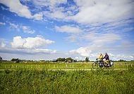 Fahrradtour Holland, Fahrradtour durch malerische Landschaft in Südholland., Fahrradfahrer in idyllischer Landschaft unter blauem Himmel in Holland.