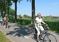 Unterwegs mit dem Fahrrad, Fahrradtour durch Südholland, vorbei an Windmühlen und Natur., Radfahrer genießen die Landschaft in Südholland bei Sonnenschein.