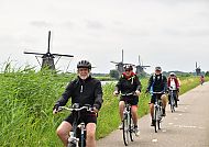 Kinderdijk, Radfahrer in Kinderdijk vor malerischen Windmühlen.