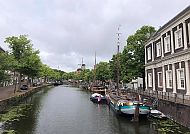 Schiedam, Idyllischer Kanal in Schiedam mit Booten und Windmühle im Hintergrund., Malerischer Kanal in Schiedam mit historischen Booten und Windmühle.