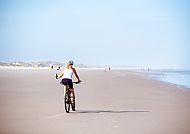 Radeln am Strand, Radfahren am weiten, sonnigen Strand von Nordholland., Radfahrer genießt sonnigen Strand in Nordholland.