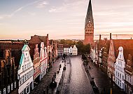 Lüneburg Am Sande, Historische Fassaden und St. Johanniskirche in Lüneburg bei Sonnenuntergang.