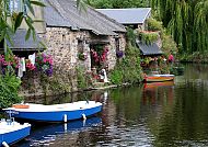 dyllische Flusslandschaft mit Booten und blumengeschmückten Häusern