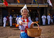 Alkmaar, Fröhliche Frau in traditioneller Kleidung mit Korb in Alkmaar., Fröhliche Frau in Tracht mit Korb in Alkmaar.