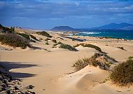 Fuerteventura, Weite Sanddünenlandschaft auf Fuerteventura unter blauem Himmel., Weite Sanddünen und Küstenlandschaft auf Fuerteventura.