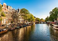 Amsterdam, Idyllische Grachtenansicht in Amsterdam bei Sonnenschein., Amsterdam-Kanal bei Sonnenschein, gesäumt von historischen Gebäuden.