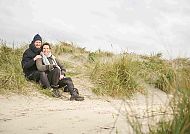 Paar am Strand, Paar genießt entspannte Zeit in den Dünen von Norderney., Paar genießt idyllischen Strandmoment auf Norderney.