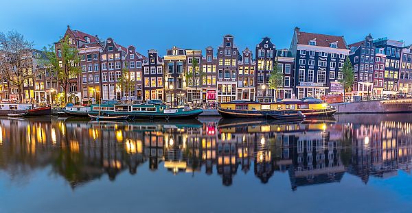 Amsterdam, Beleuchtete Grachtenhäuser in Amsterdam spiegeln sich im Wasser.