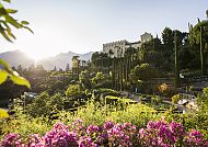 Gärten von Schloss Trauttmansdorff,, Schloss Trauttmansdorff bei Sonnenuntergang, umgeben von blühenden Gärten.