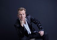 Jürgen Weber in elegantem Anzug vor dunklem Hintergrund