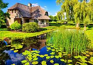 Ausflugstipp: Giethoorn, Idyllisches Haus am Wasser in Giethoorn, umgeben von Natur., Idyllische Landschaft mit Reetdachhaus und Teich in Giethoorn.